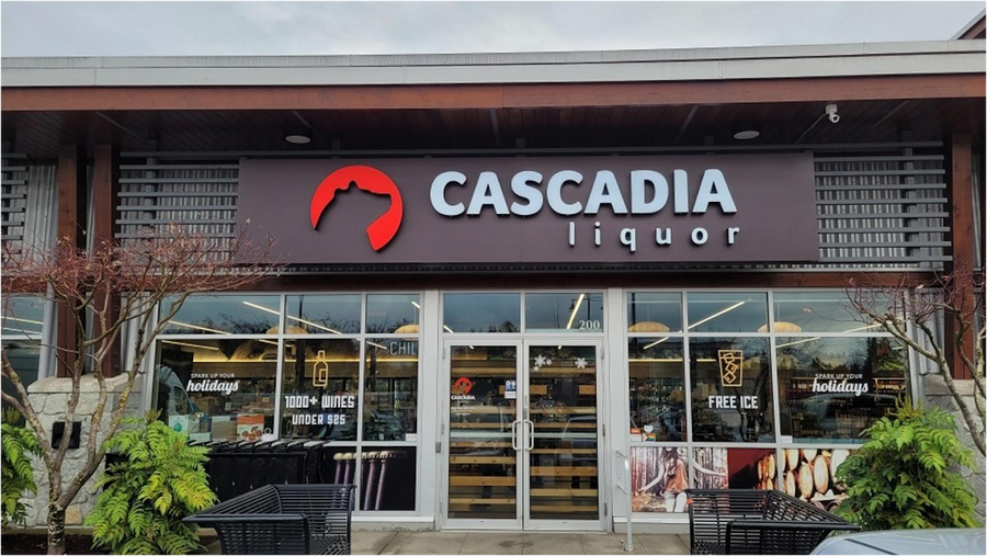 Storefront of Cascadia Liquor Courtenay with large signage and glass entrance, surrounded by greenery.