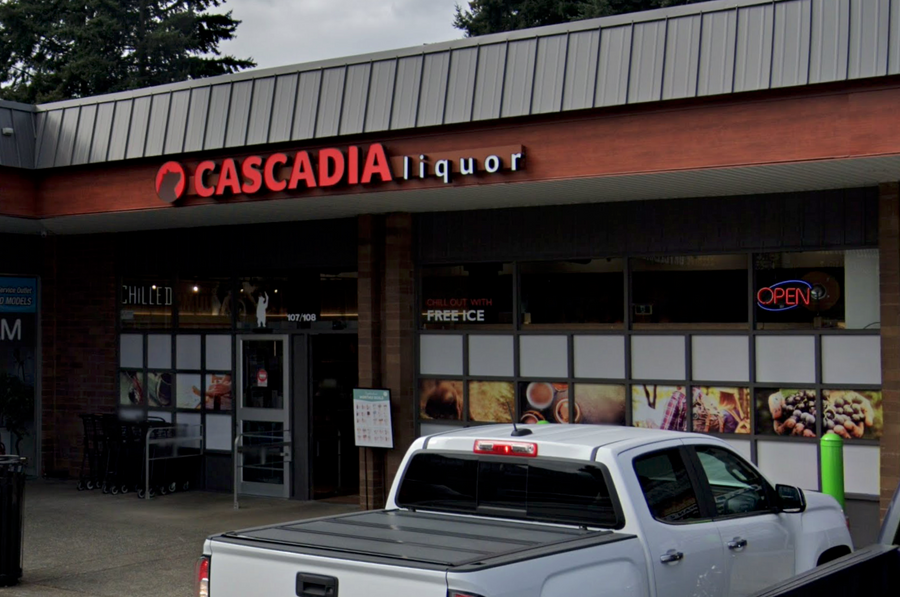 Exterior of Cascadia Liquor Hatley Park store with a red and white sign. A white pickup truck is parked in front, and an "open" sign is visible in the window.