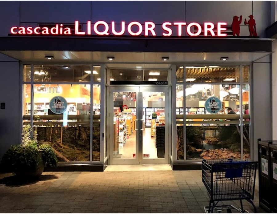 The Uptown Cascadia Liquor storefront is well-lit, showcasing various products inside. A shopping cart is parked outside.
